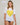 Woman wearing a white short sleeve rashguard with a yellow heart design on the front. 