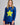 Woman wearing a blue long-sleeve shirt with a yellow star and dark shorts on a gray background