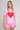 A woman modeling a light pink short-sleeve t-shirt with a large red heart graphic on the front, paired with matching pink shorts, against a light gray studio background.