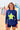 Woman wearing a blue long-sleeve top with a yellow star on a beach.