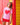 A woman wearing a light pink t-shirt style rashguard with a large red heart graphic and red shorts, leaning against a colorful red and yellow wooden wall.