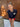 Woman wearing a navy blue long sleeved rashguard with a white heart design and the word AMOUR in red overlayed on the heart, standing in front of timber cupboards.